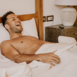 Masturbation Vorteile. Symbolbild: Mann liegt erfreut im Bett Masturbation benefits. Symbolic image: Man lying in bed with pleasure