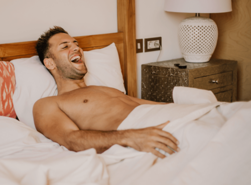 Masturbation Vorteile. Symbolbild: Mann liegt erfreut im Bett Masturbation benefits. Symbolic image: Man lying in bed with pleasure