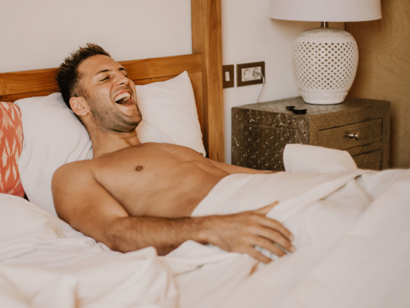 Masturbation Vorteile. Symbolbild: Mann liegt erfreut im Bett Masturbation benefits. Symbolic image: Man lying in bed with pleasure