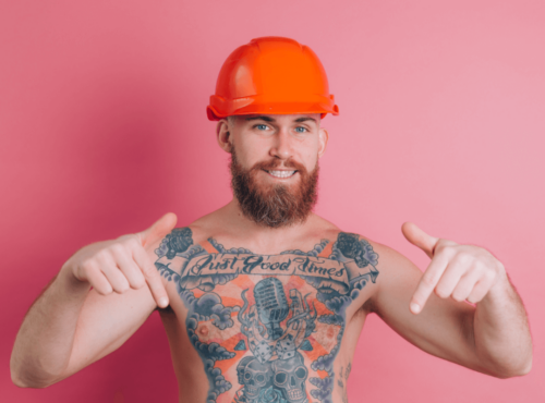 Penis Namen Symbolbild: tätowierter Mann mit freiem Oberkörper deutet nach unten (wo man - nicht auf dem Bild ersichtlich - sein Geschlechtsteil vermutet) / Penis names Symbolic image: tattooed man with bare upper body pointing downwards (where - not visible in the picture - his genitals are assumed to be)