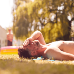 Damm sonnen. Symbolbild: Mann liegt oberkörperfrei auf einer Wiese in der Sonne. English: Perineum Sunning. Symbolic image: Man lying bare-chested in the sun on a meadow.