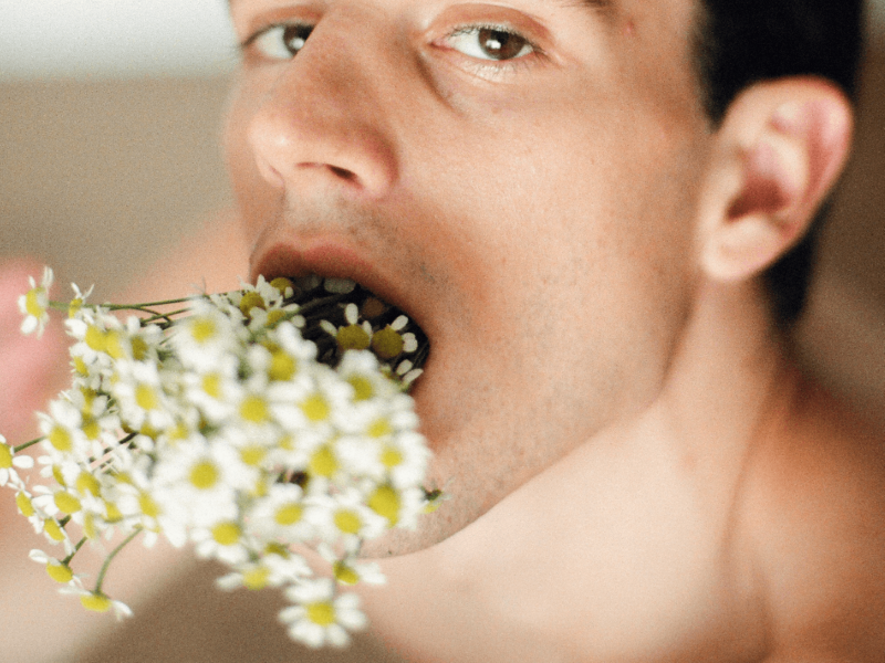 Deep Throat Tipps für Empfänger. Symbolbild: Ein Mann steckt sich einen Strauß Blumen tief in den Hals und schaut lüstern. Englisch: Deep throat tips for recipients. Symbolic image: A man sticks a bunch of flowers deep down his throat and looks lustfully.