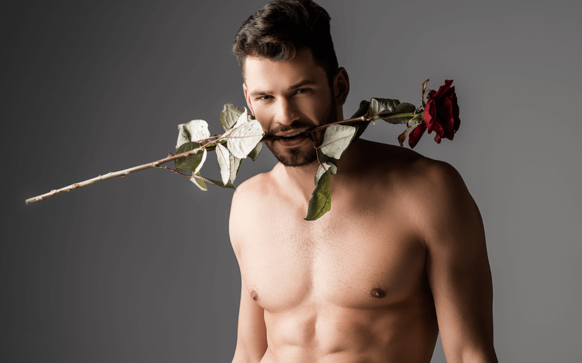 Analprolaps und Rosebud. Symbolbild: Mann mit nacktem Oberkörper trägt eine Rose im Mund. Englisch: Anal prolapse and rosebud. Symbolic image: Man with a naked upper body wearing a rose in his mouth.