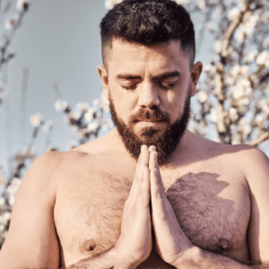 Schwule und Religion. Symbolbild: Mann mit freiem Oberkörper hat die Augen geschlossen und die Hände zum Gebet gefaltet. Englisch: Gay and religious. Symbolic image: Man with bare upper body, eyes closed and hands folded in prayer.