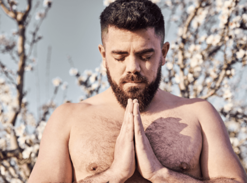 Schwule und Religion. Symbolbild: Mann mit freiem Oberkörper hat die Augen geschlossen und die Hände zum Gebet gefaltet. Englisch: Gay and religious. Symbolic image: Man with bare upper body, eyes closed and hands folded in prayer.