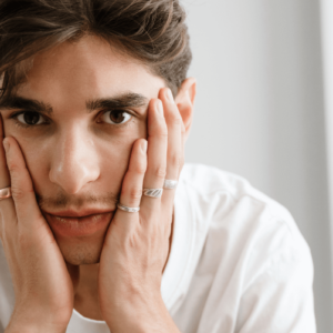 Suizid queere Menschen. Symbolbild: niedergeschlagen dreinblickender Mann hält mit den Händen sein Gesicht. Englisch: Suicide among queer people. Symbolic image: dejected looking man holding his face with his hands