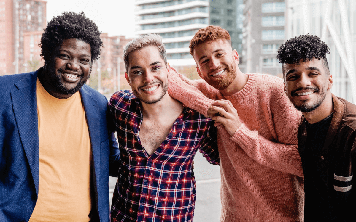 Männergruppe Symbolbild: 4 Männer unterschiedlicher Hautfarbe, Gewicht usw. lachen in die Kamera. Englisch: Men's Groups Symbolic image: 4 men of different skin color, weight, etc. laughing into the camera.