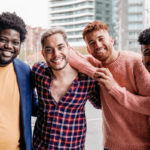 Männergruppe Symbolbild: 4 Männer unterschiedlicher Hautfarbe, Gewicht usw. lachen in die Kamera. Englisch: Men's Groups Symbolic image: 4 men of different skin color, weight, etc. laughing into the camera.