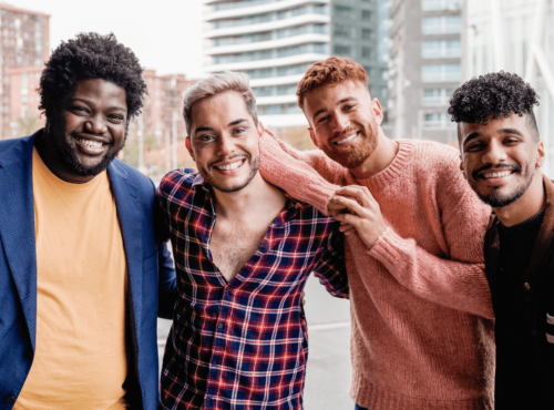 Männergruppe Symbolbild: 4 Männer unterschiedlicher Hautfarbe, Gewicht usw. lachen in die Kamera. Englisch: Men's Groups Symbolic image: 4 men of different skin color, weight, etc. laughing into the camera.