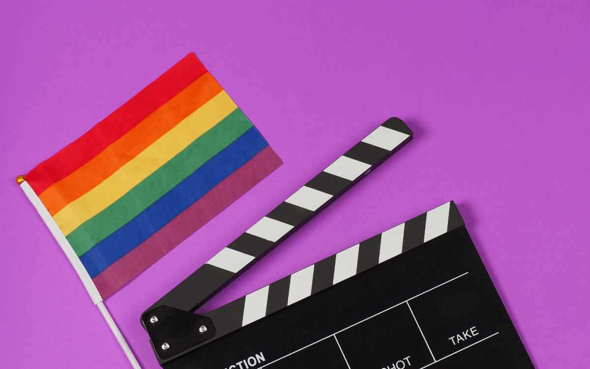 Queere Filme. Symbolbild: Filmklappe und Regenbogenfahne. Englisch: Queer movies Symbolic image: movie flap and rainbow flag.