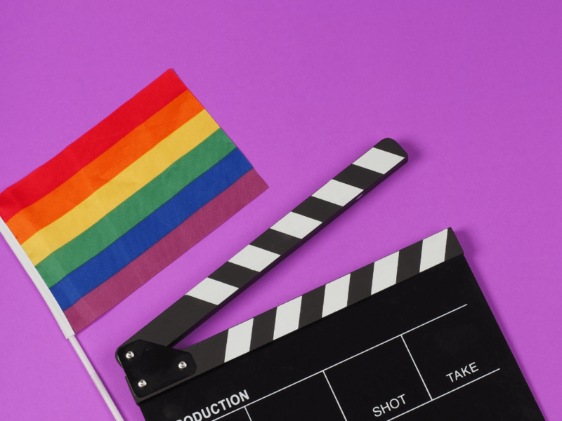 Queere Filme. Symbolbild: Filmklappe und Regenbogenfahne. Englisch: Queer movies Symbolic image: movie flap and rainbow flag.