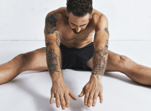 Autofellatio Symbolbild: Ein an den Armen tätowierter Mann, der nur mit Unterhose bekleidet ist, macht Dehnübungen. Englisch: Self-sucking symbol picture: a man tattooed on his arms, wearing only underpants, does stretching exercises.