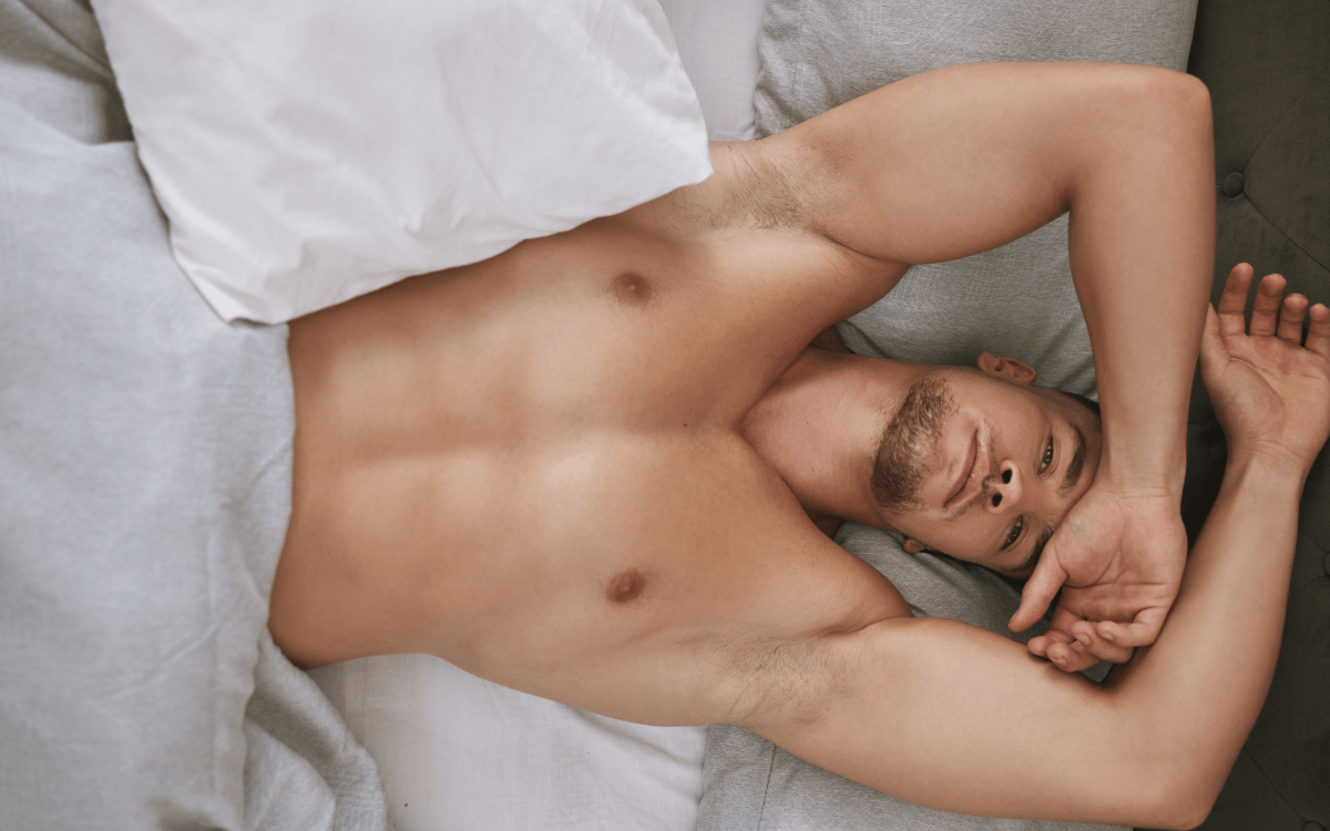 Gooning Masturbation. Symbolbild: Ein Mann liegt mit nacktem Oberkörper im Bett und ist sichtlich erschöpft. Englisch: Gooning Masturbation. Symbolic picture: A man lies in bed with a naked upper body and is visibly exhausted.