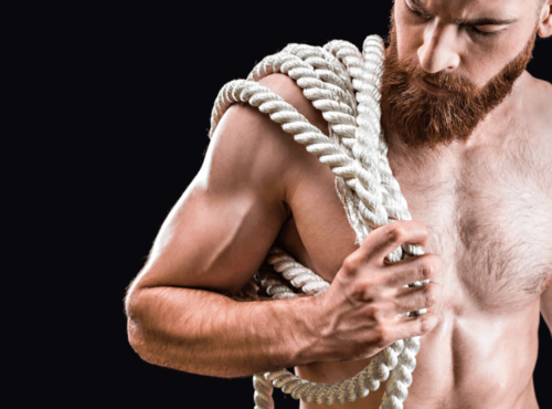 Rigger BDSM oder Rope Top. Symbolbild: Ein Mann mit freiem Oberkörper trägt ein dickes Seil. Englisch: Rigger or rope top. Symbolic image: a shirtless man carries a thick rope.