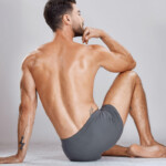 Prostatamassage Symbolbild: Ein Mann, nur mit Unterhose bekleidet, sitzt mit dem Rücken zur Kamera auf dem Boden. Englisch: Prostate massage Symbolic image: A man wearing only underwear is sitting on the floor with his back to the camera.