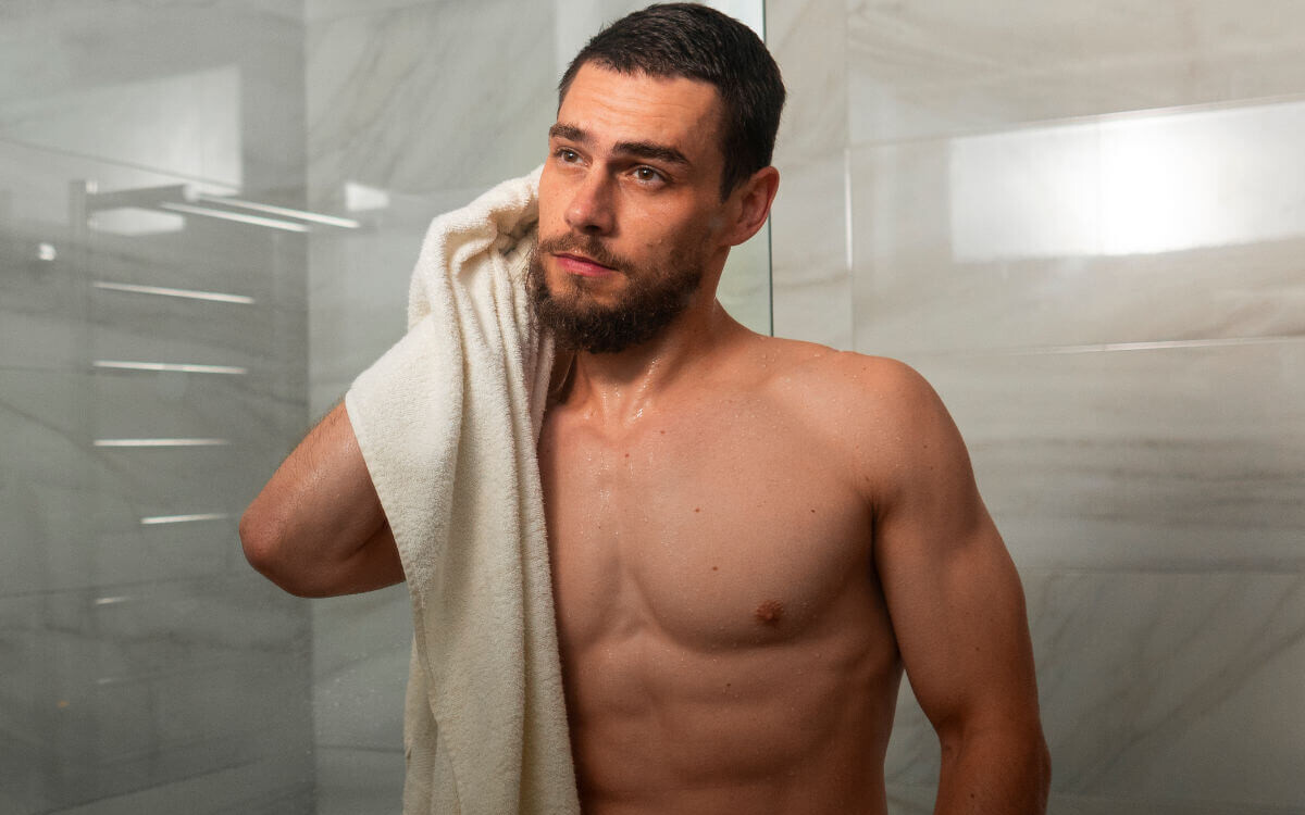 Analsex Reinigung Symbolbild: ein Mann kommt aus der Dusche und trocknet sich mit dem Handtuch ab. Englisch: Anal sex cleaning Symbolic image: a man comes out of the shower and dries himself with a towel.