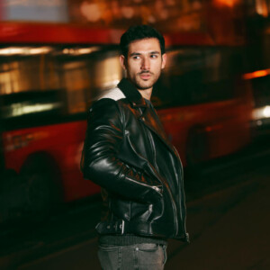BDSM Benefits Symbolbild: Ein Mann schaut zurück richtung Kamera. Hinterhin fährt ein Bus vorbei. Englisch: BDSM benefits Symbolic image: A man looks back toward the camera. A bus drives past behind him.